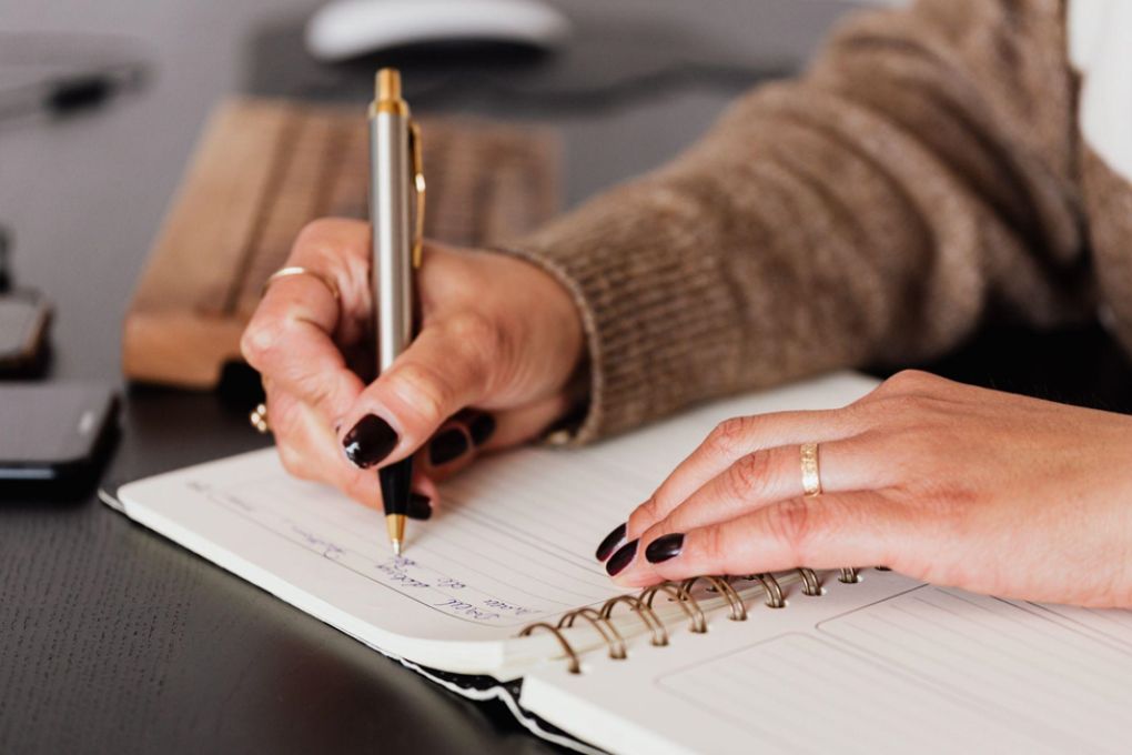 A girl writing in a notebook with a founting pen